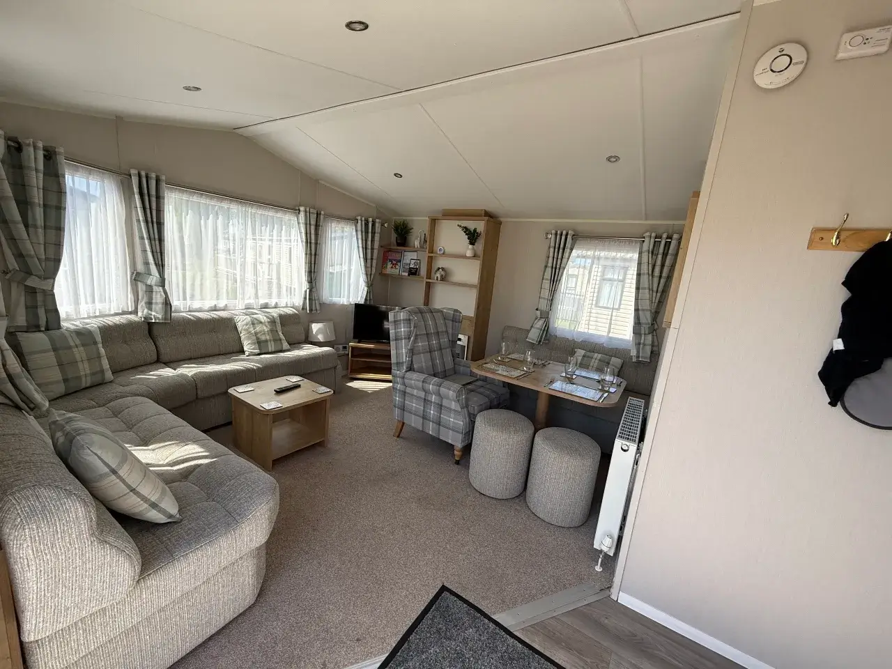 Lounge with grey corner sofa, dining table, and armchair by windows.