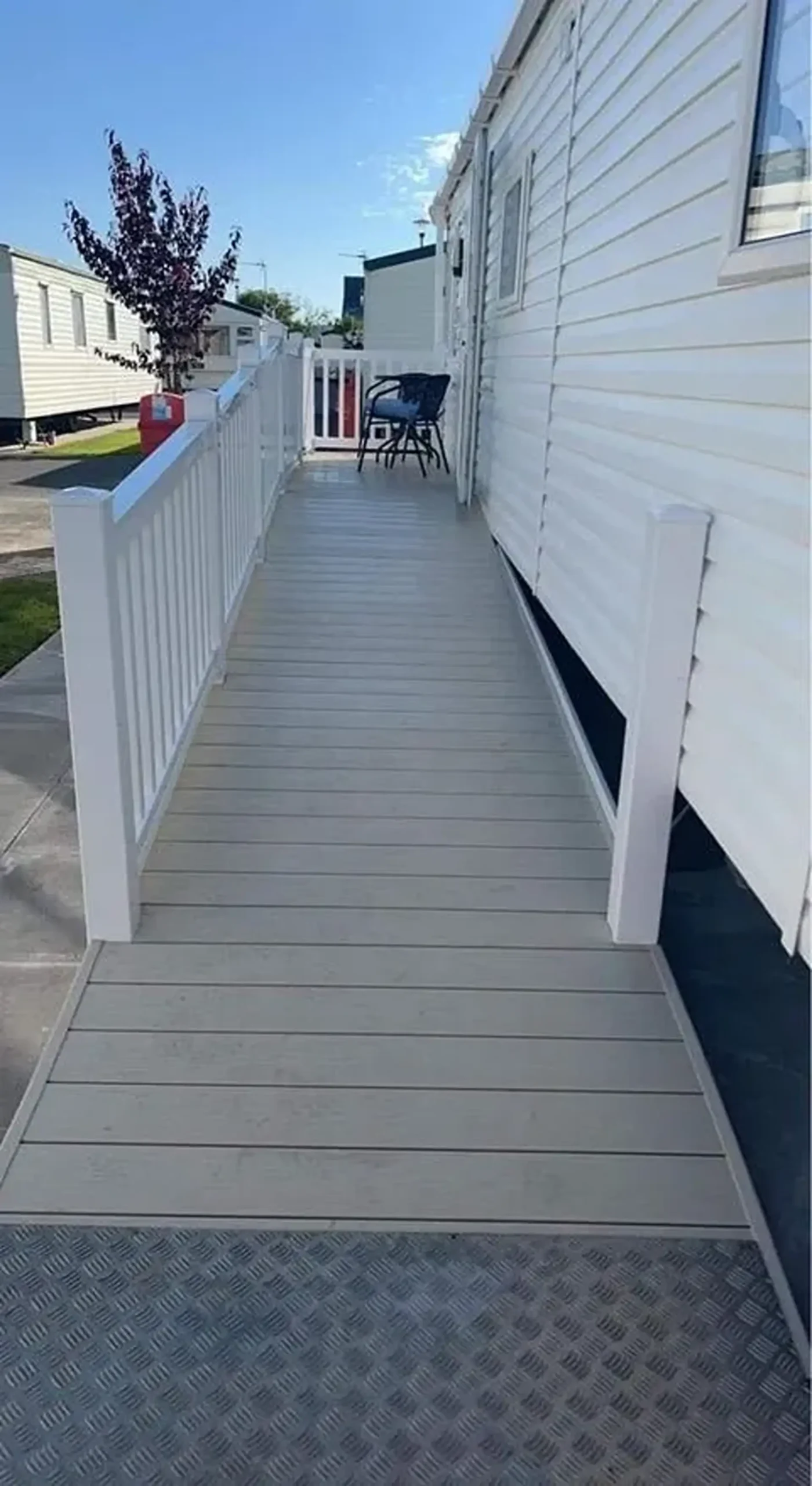 Wheelchair ramp with white railings leading to holiday home entrance.