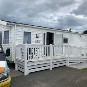 White static holiday home with wraparound accessible ramp and decking.