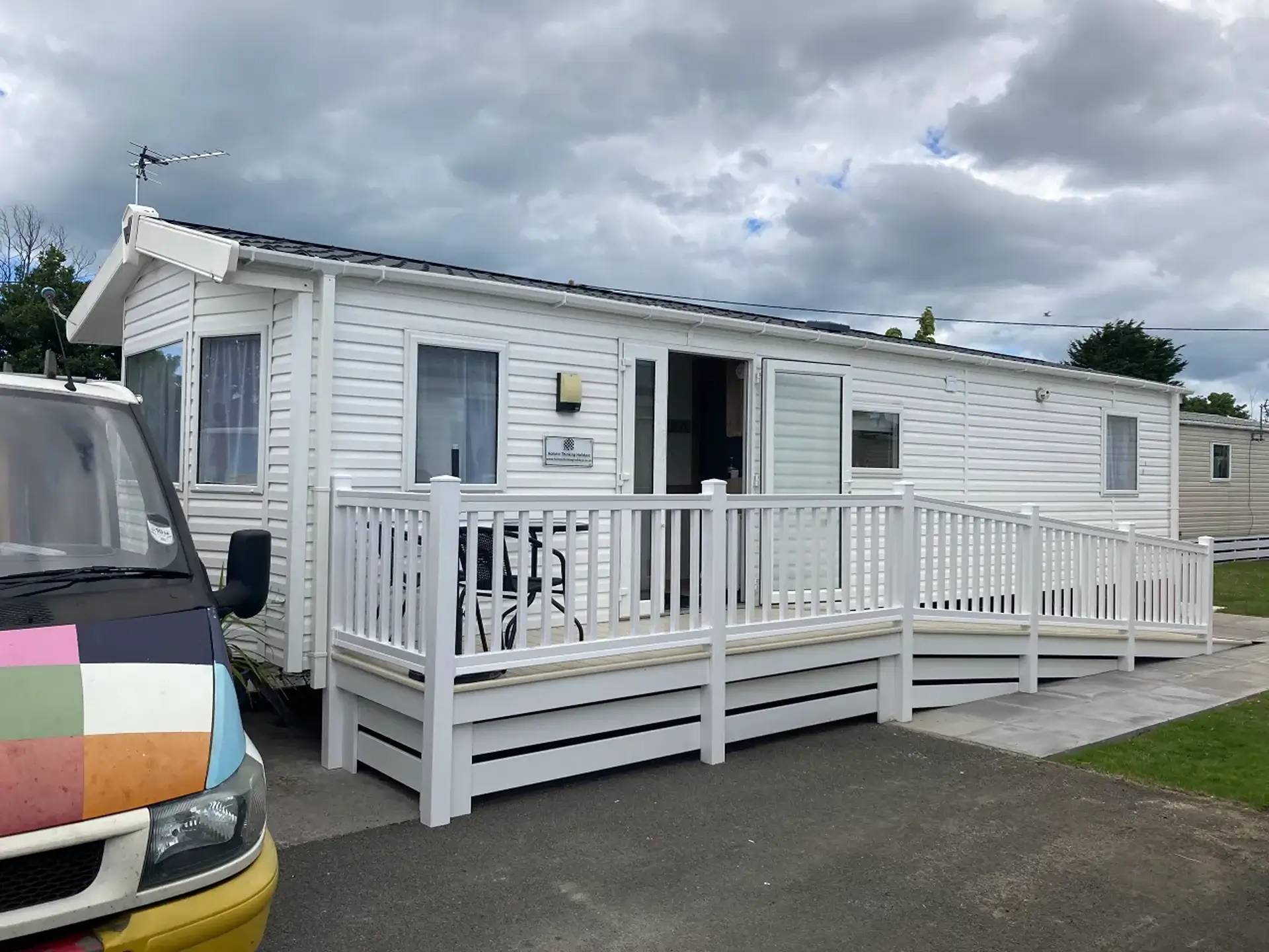 White static holiday home with wraparound accessible ramp and decking.