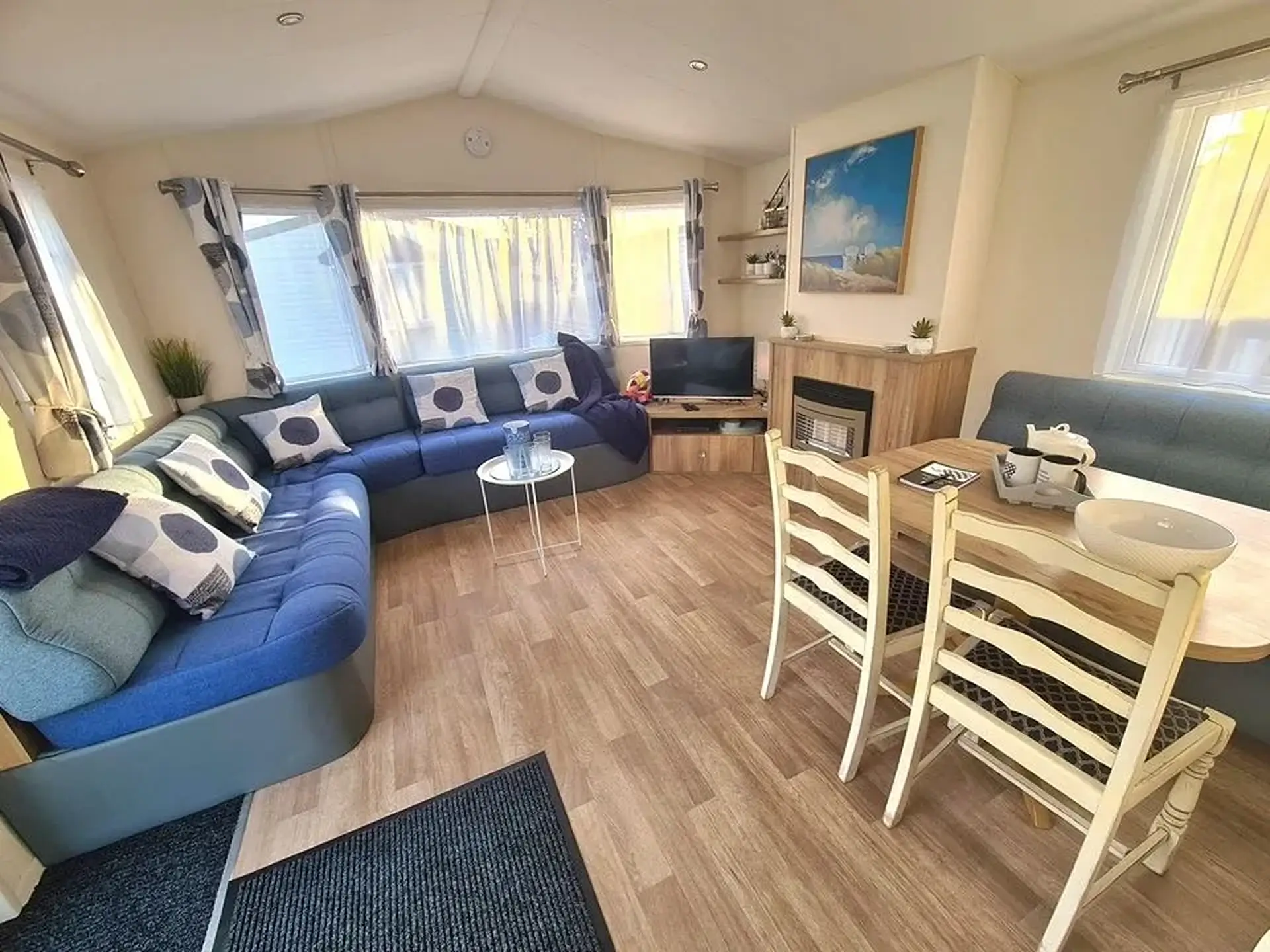 Lounge with blue L-shaped sofa, TV, fireplace, and dining table.