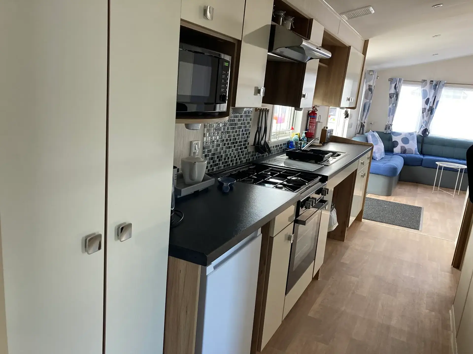 Kitchen with hob, oven, microwave, and mosaic splashback.
