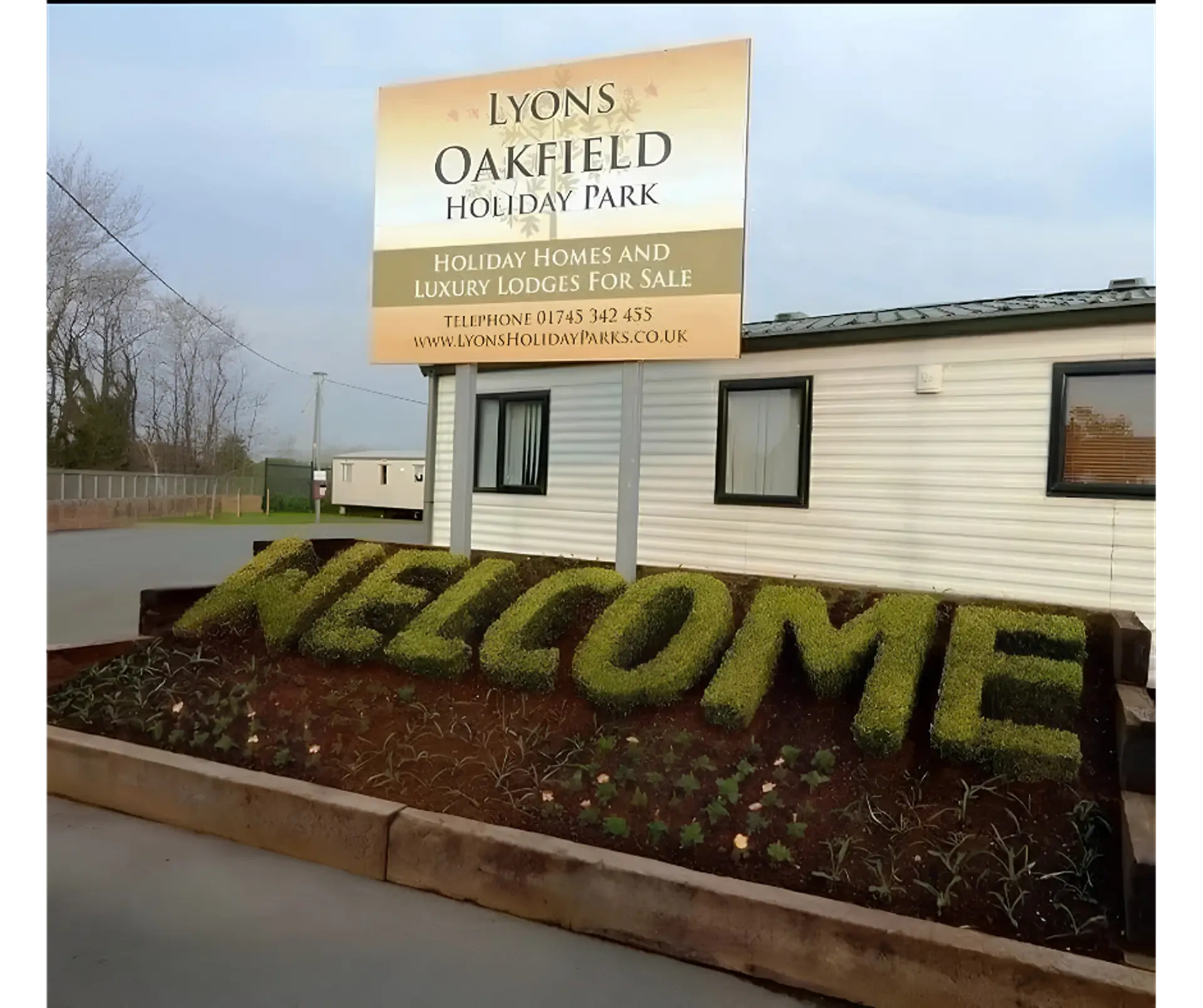 "Lyons Oakfield Holiday Park" entrance sign with hedge "WELCOME" display.