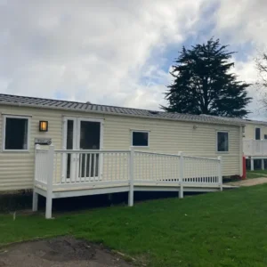 Cream static caravan named "Rio" with wheelchair ramp and decking.