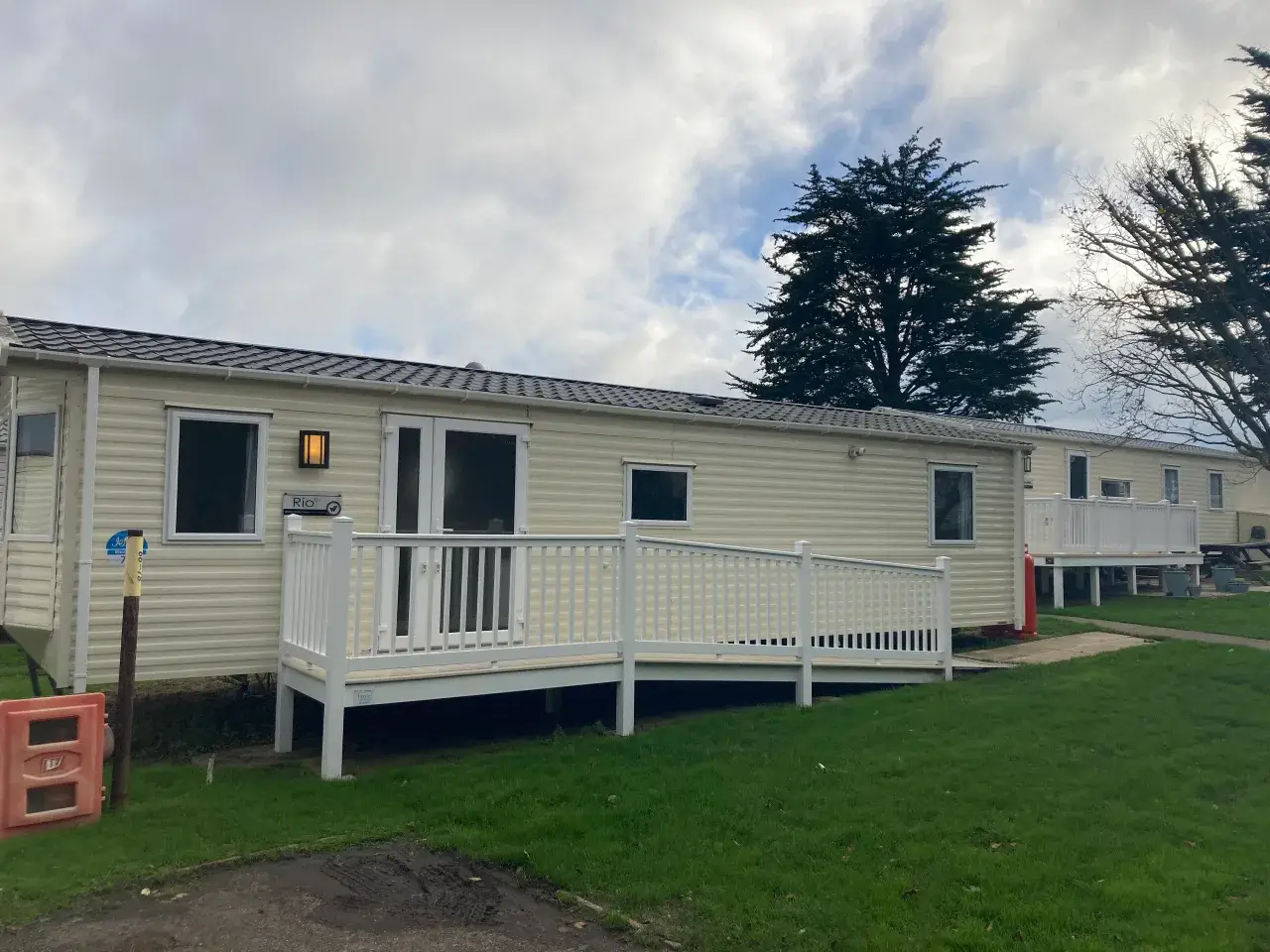 Cream static caravan named "Rio" with wheelchair ramp and decking.
