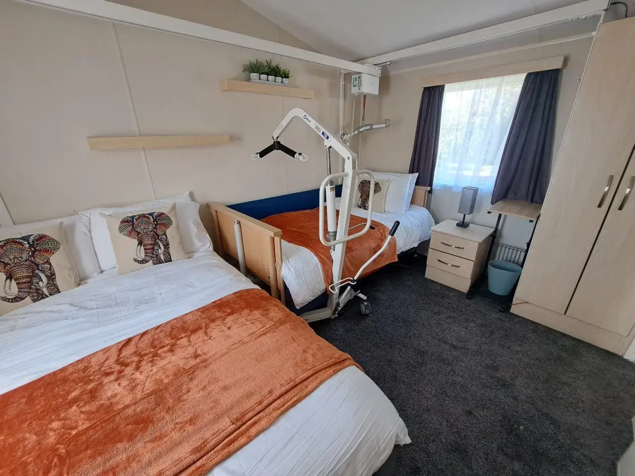Bedroom with adjustable bed, mobile hoist, and wardrobe.