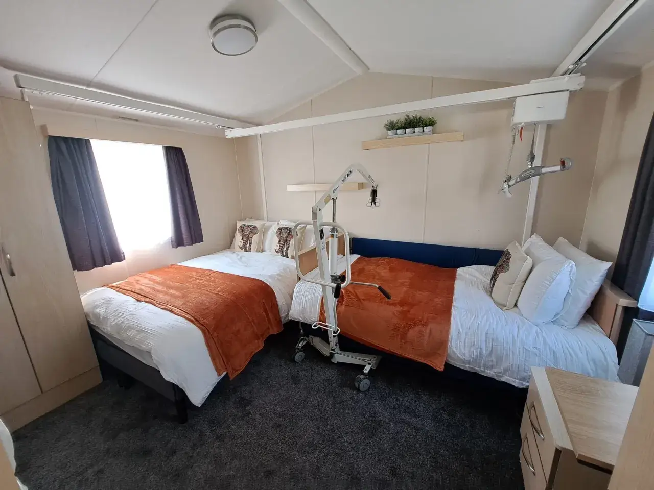 Twin room with mobile hoist positioned between two beds.