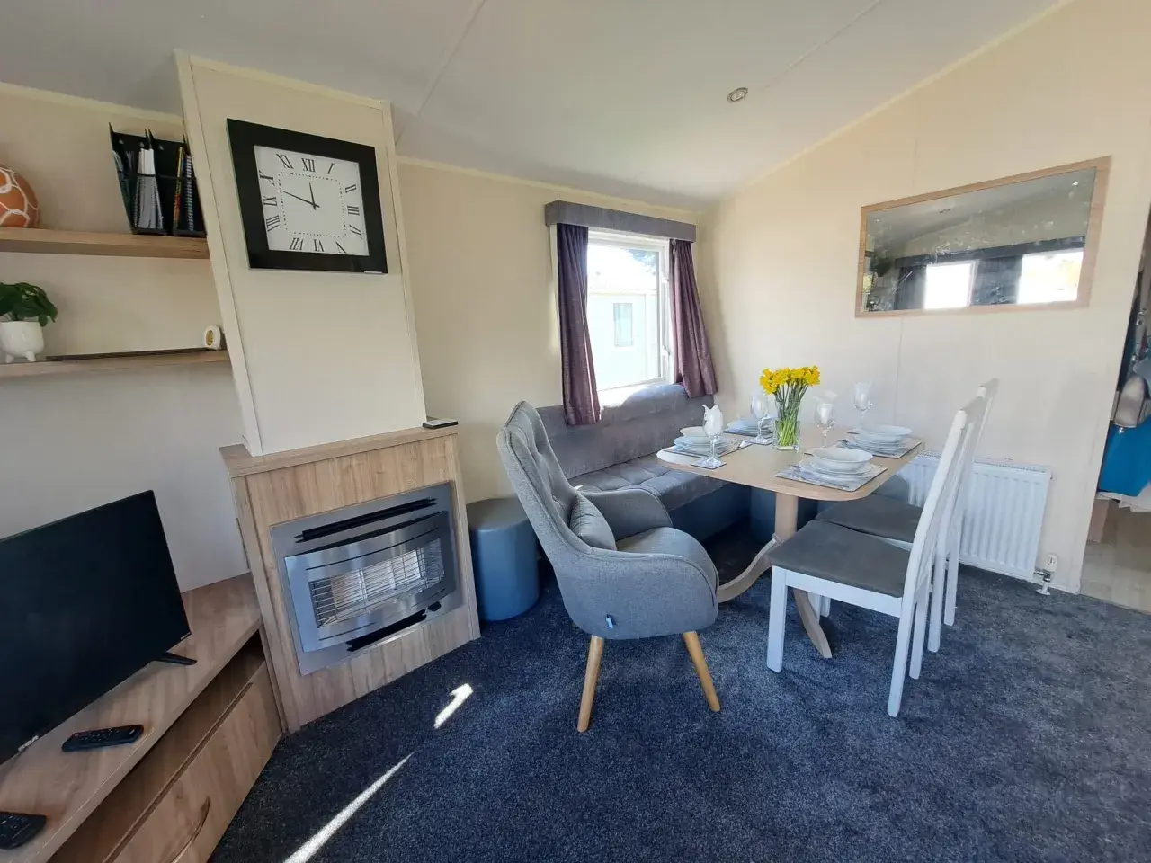 Dining nook with clock, gas fire, and table set for four.