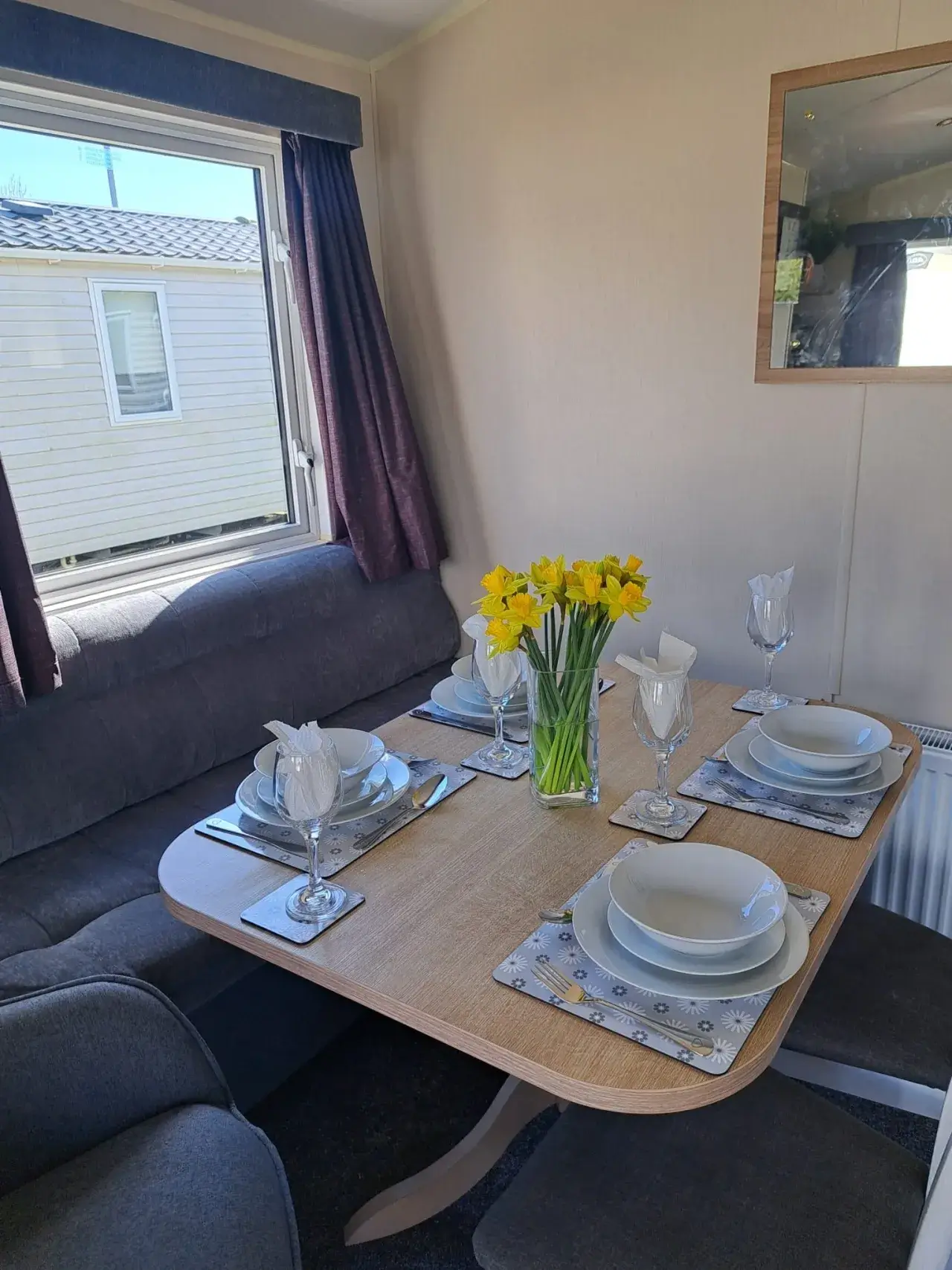 Close-up of dining table set with daffodils, plates, and wine glasses.