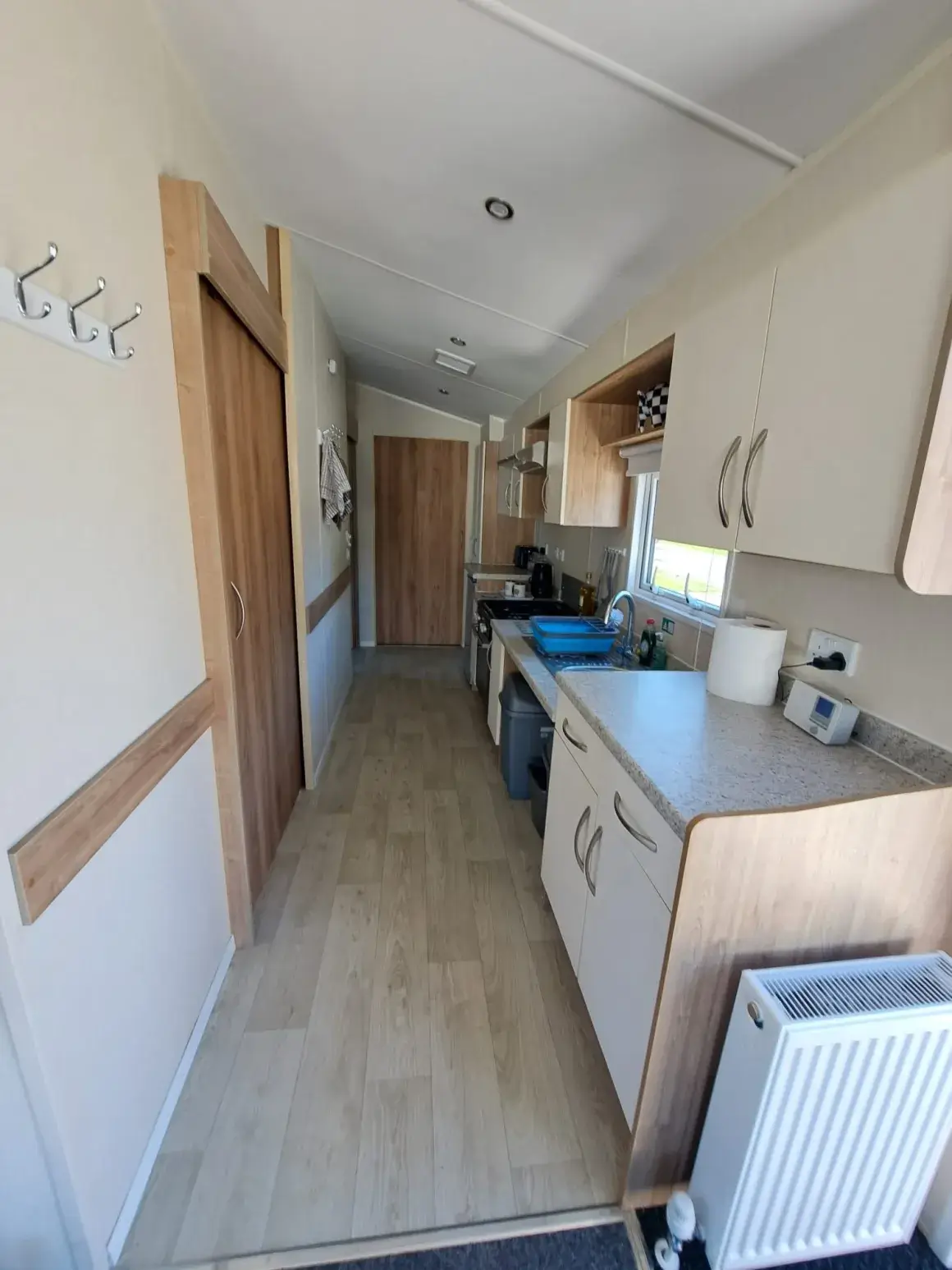 Narrow hallway leading to galley kitchen with sink and hob.