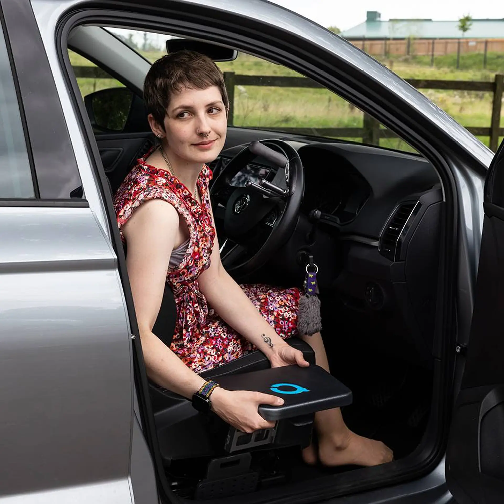 Woman seated in car's driver seat, feet resting on the transfer plate on the floor.