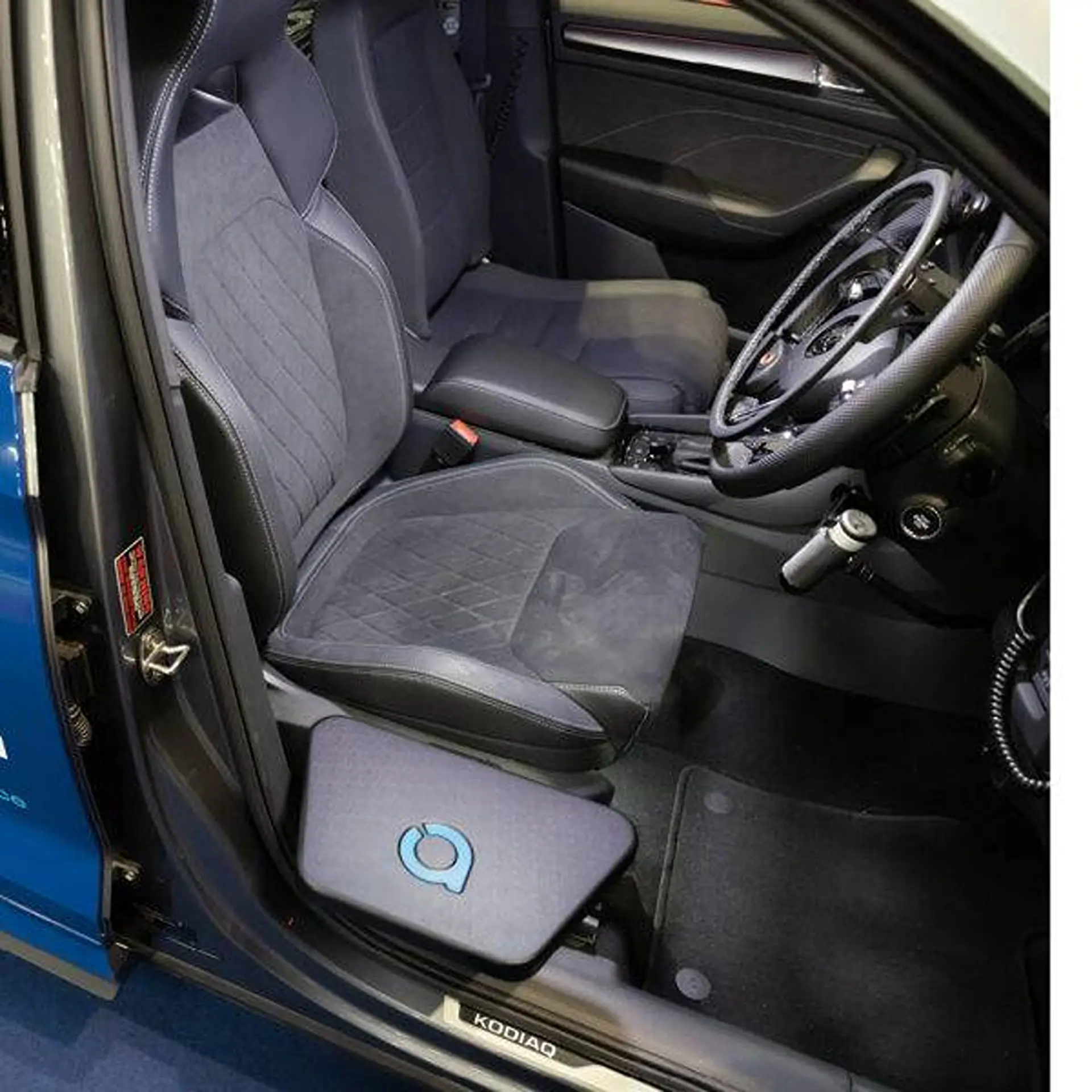 Interior view of a car's front seat and footwell showing the transfer plate mounted on the floor.
