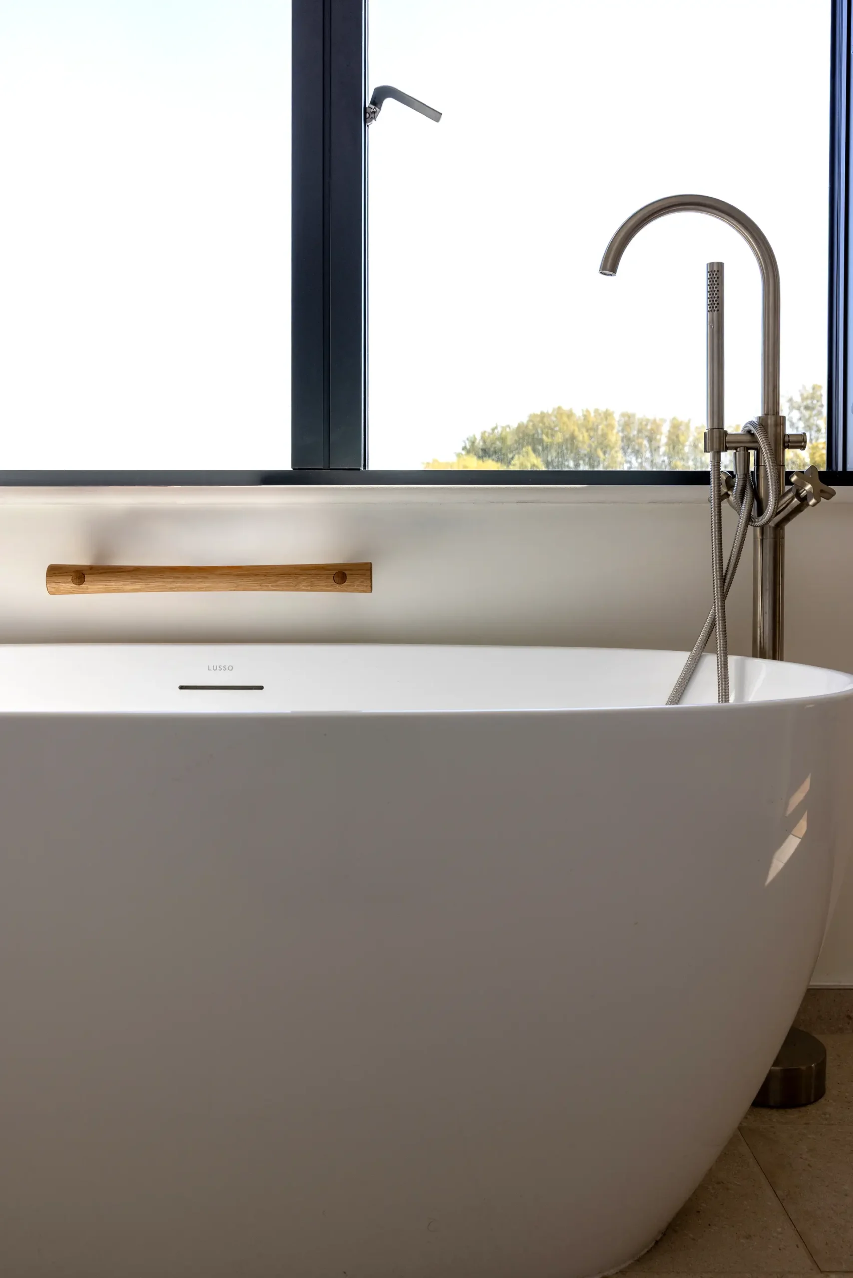 Oak grab rail mounted beside a freestanding bathtub with tap.