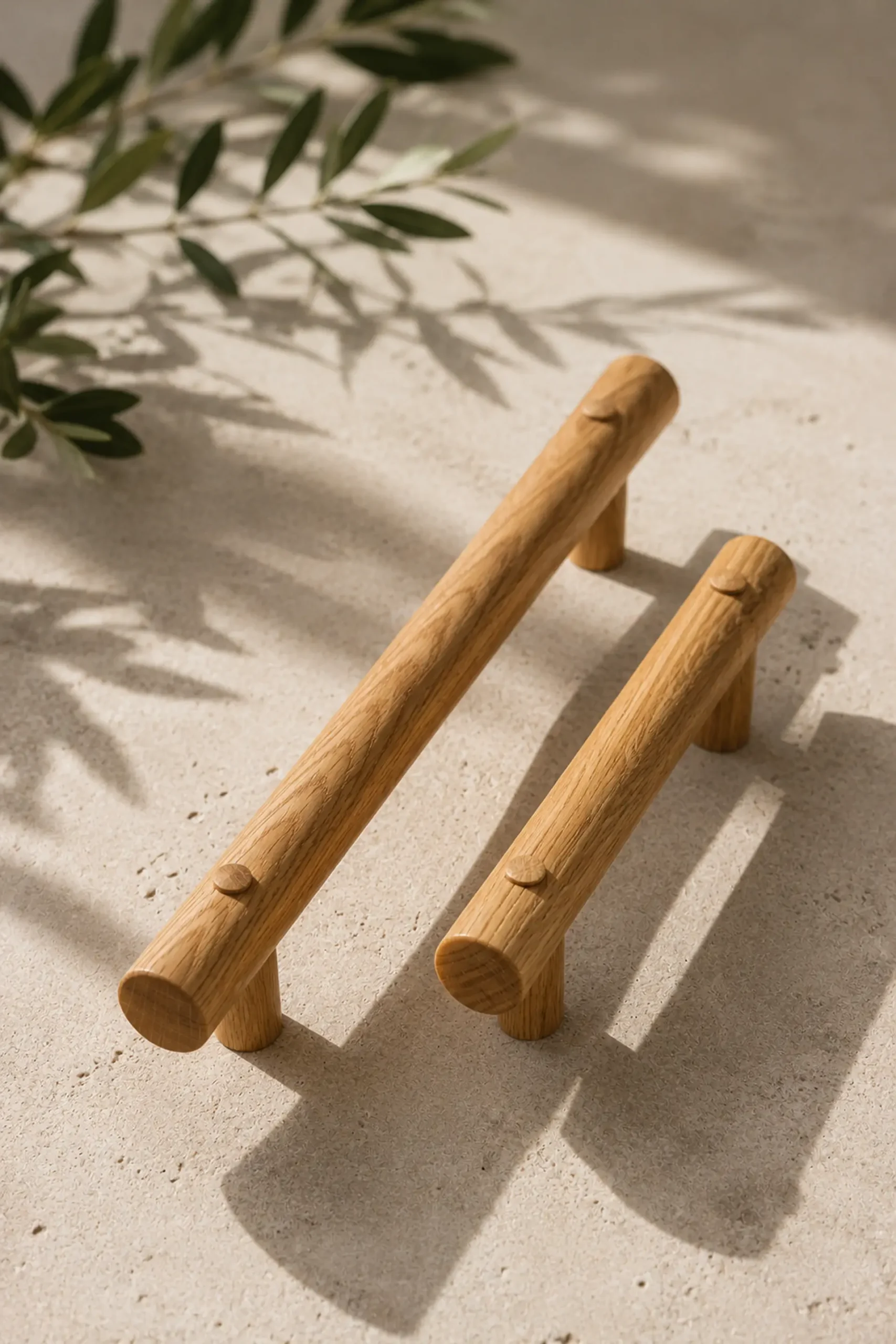 Two straight oak grab rails standing on sand with olive leaves.