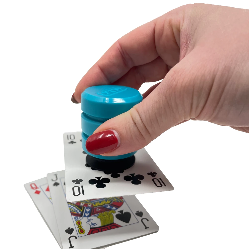 Hand pressing teal grip tool onto stack of playing cards.