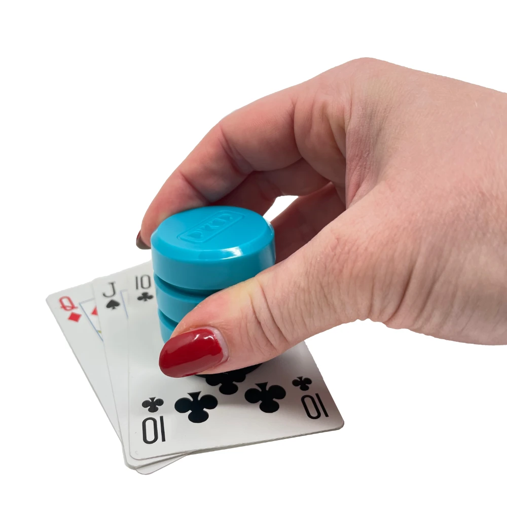 Hand picking up teal grip tool from playing cards.