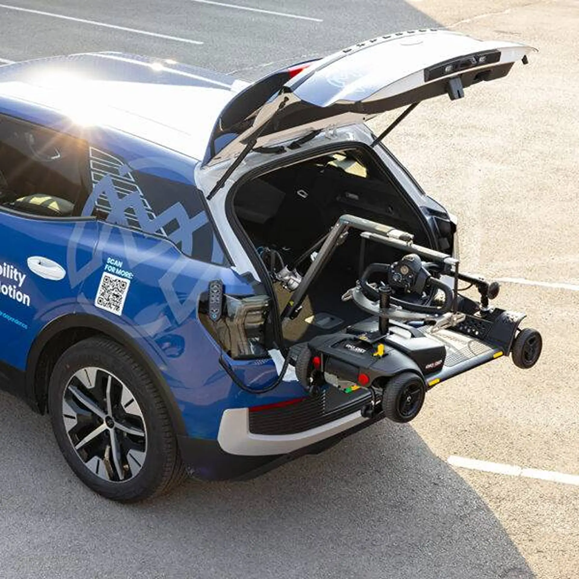 Overhead view of the lifter arm extending from an SUV's boot to hold a mobility scooter.