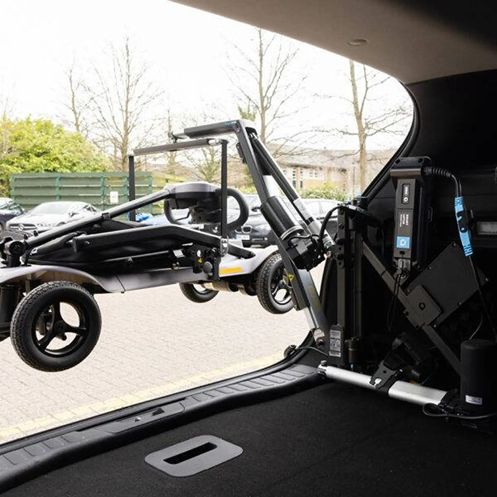 Interior view of the lifter arm swung out with a scooter suspended outside the car.