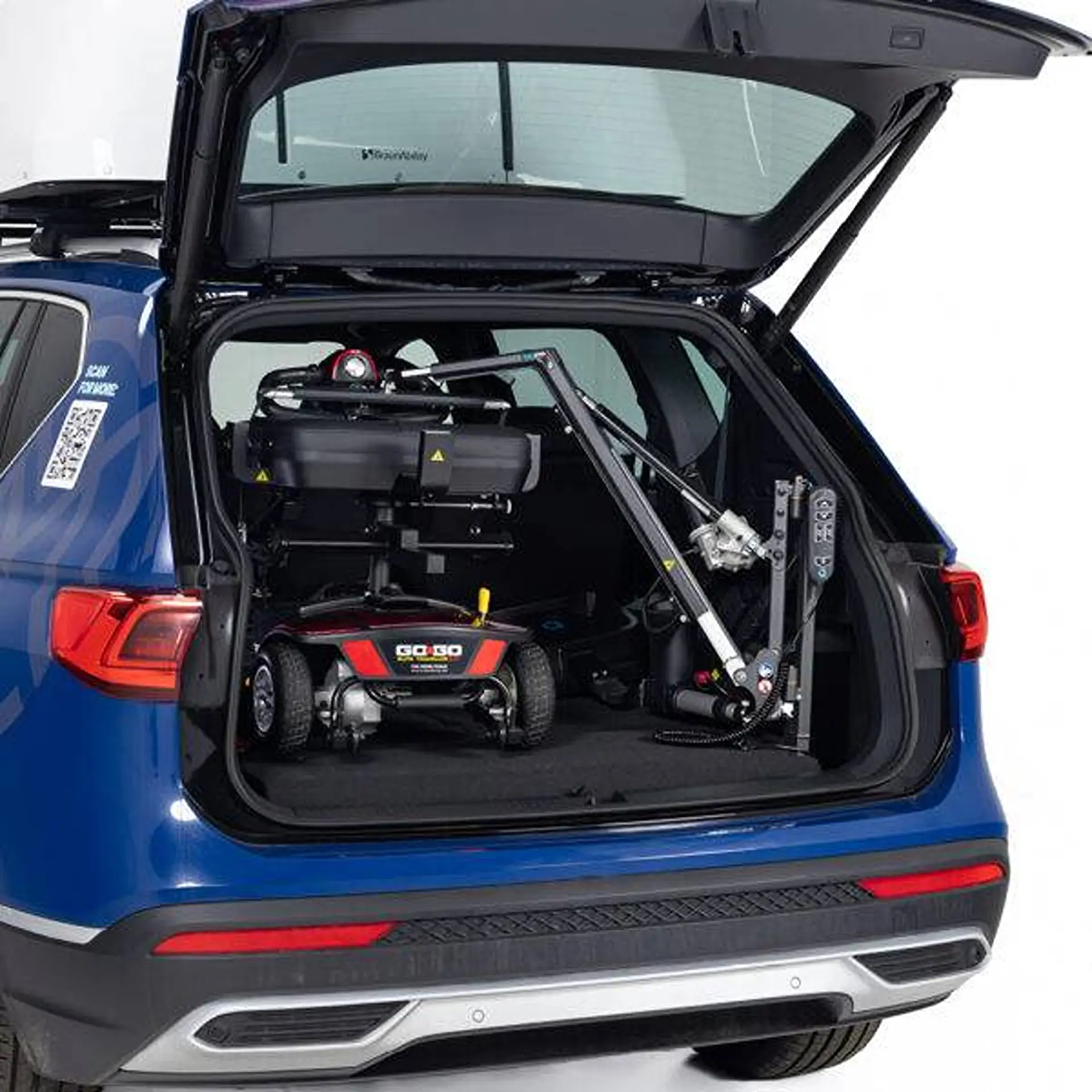 Folded scooter secured inside a blue SUV's boot next to the lifter arm.