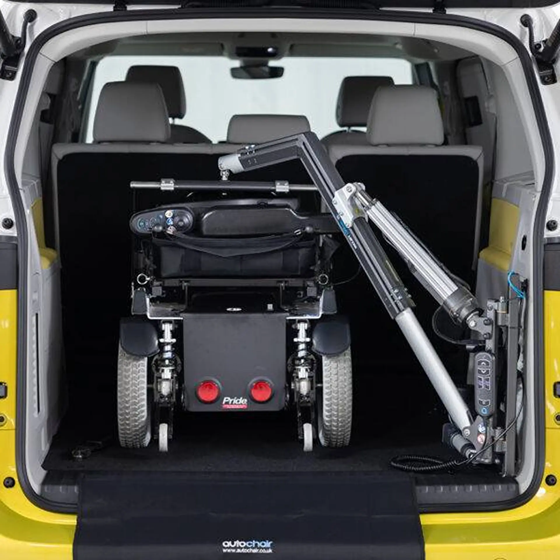 Powered wheelchair loaded into a car's boot via the lifter arm, viewed from behind.