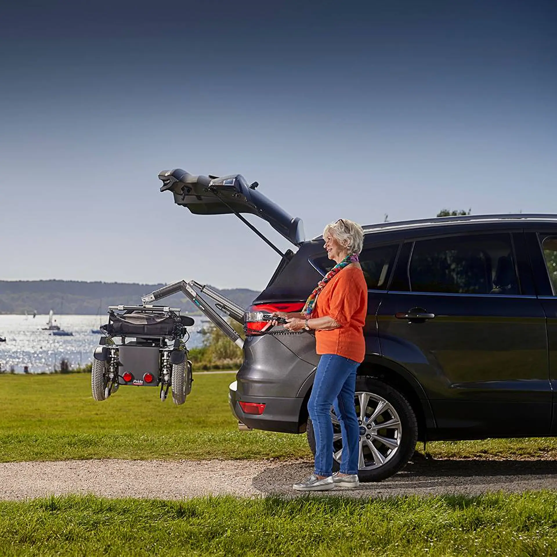 Powered wheelchair loaded into a car's boot via the lifter arm, viewed from behind.