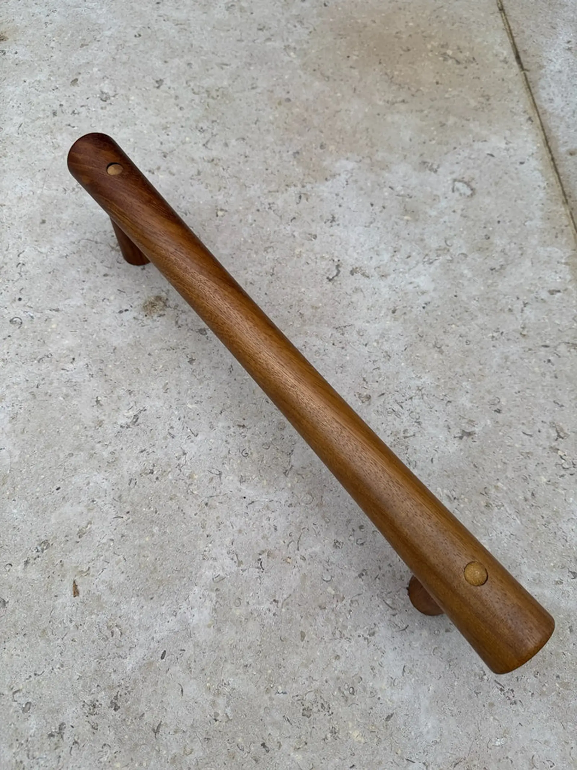 Walnut-toned grab rail on a stone floor.