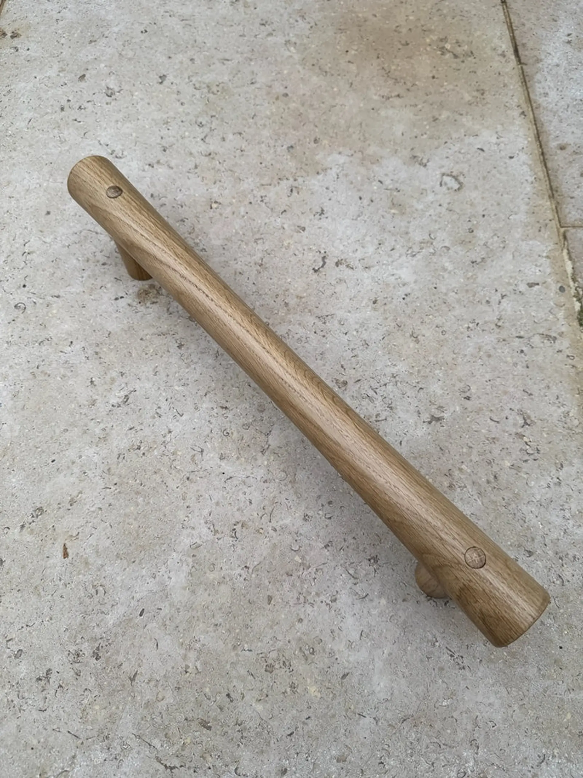 Walnut-toned grab rail on a stone paved surface.