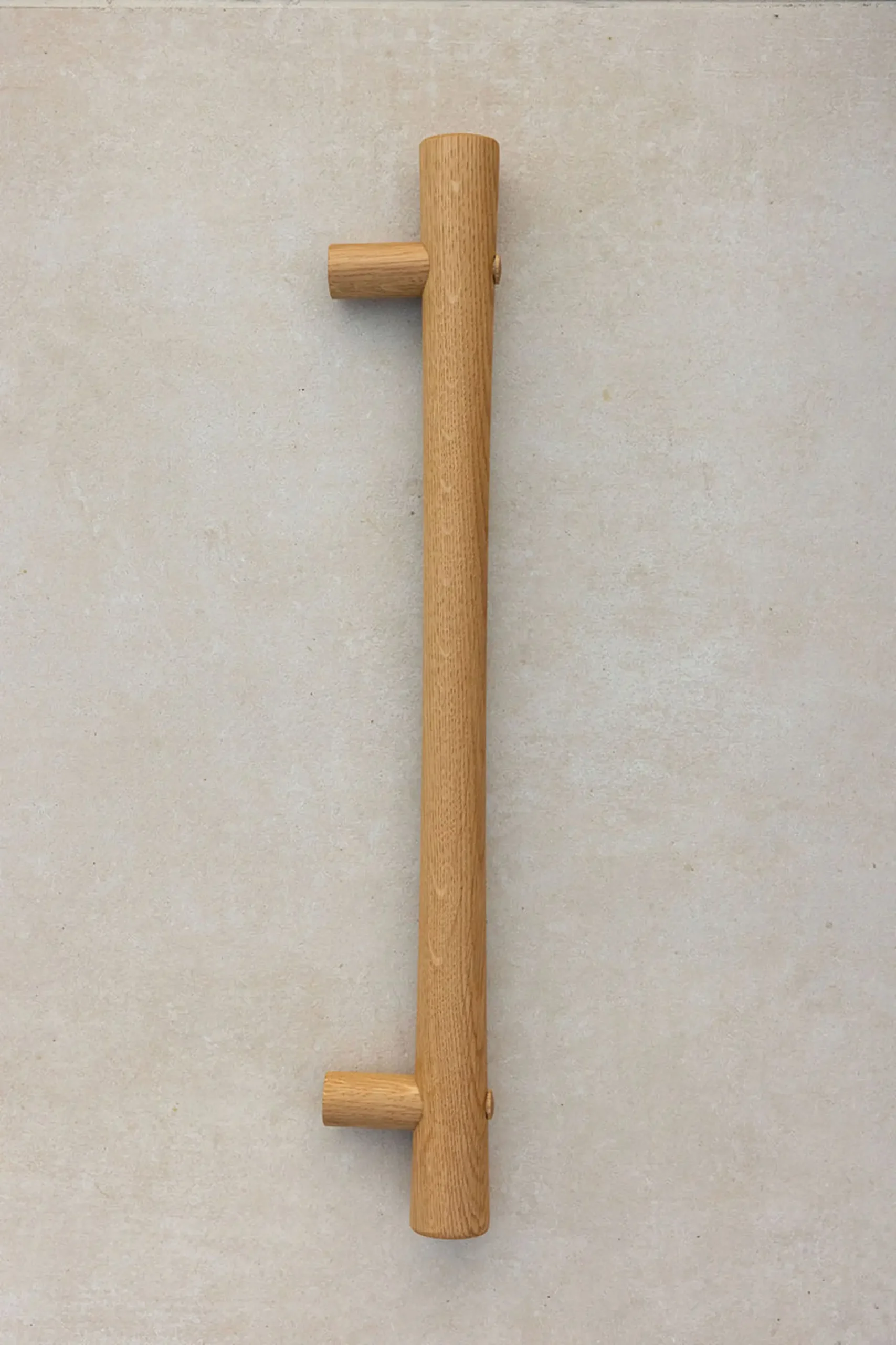 Full-length oak grab rail mounted vertically on a concrete wall.