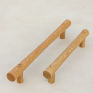 Two oak grab rails with T-ends standing upright on a light surface.