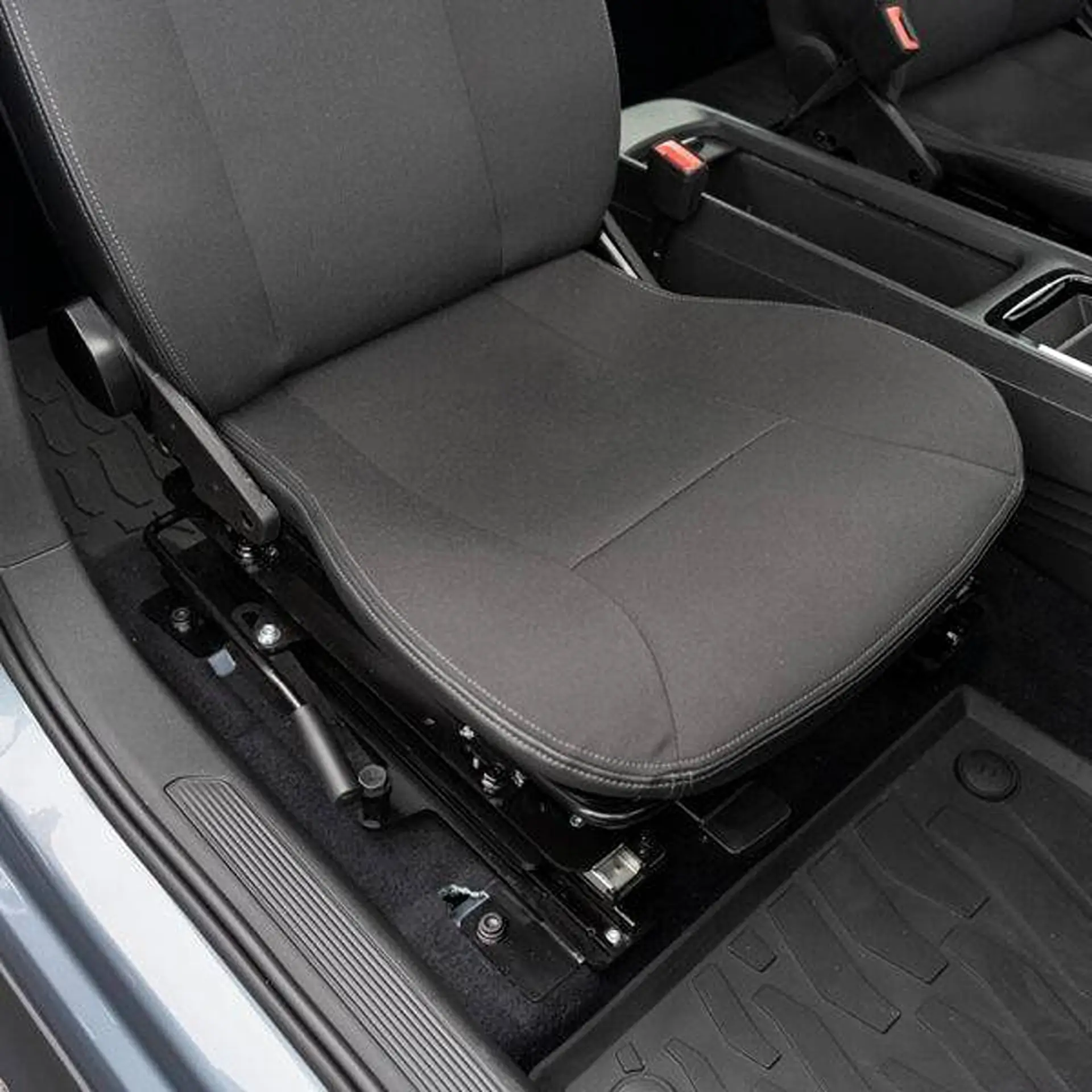 Close-up of the swivel seat base installed under a car's front seat.