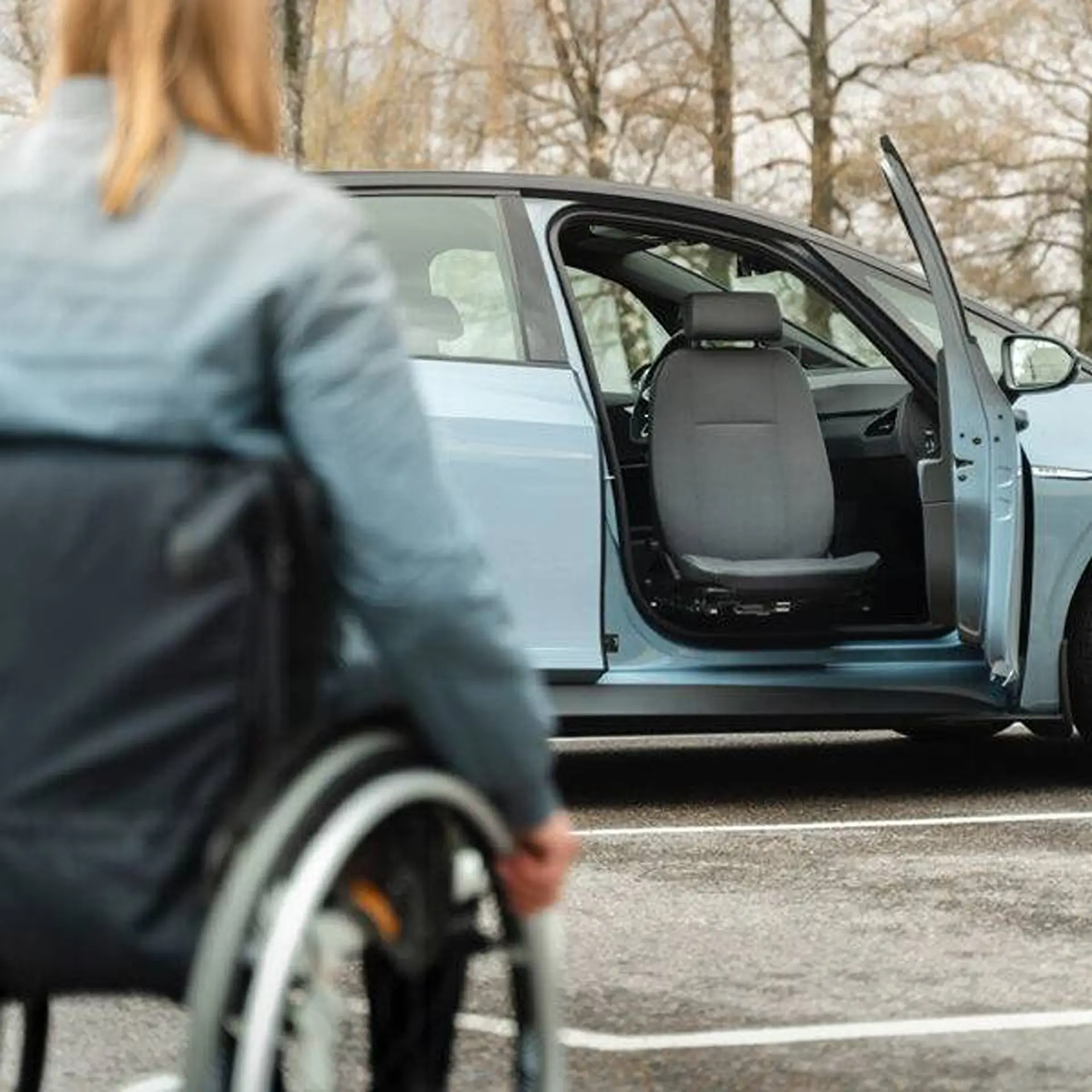 Wheelchair user viewing a car with its front seat swivelled out through the open door.