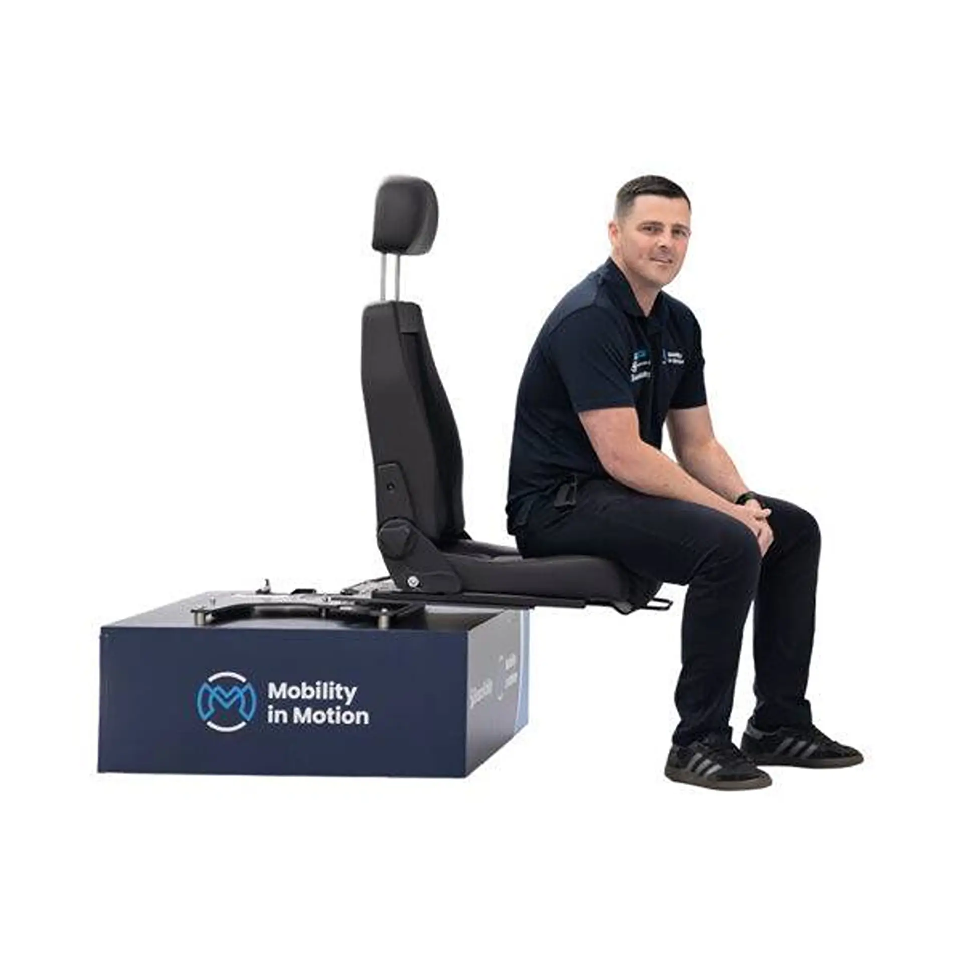 Man sitting on a demo swivel seat mounted on a display plinth, studio background.