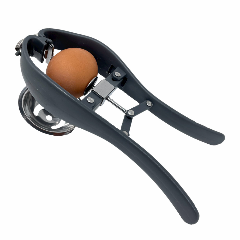 Hand-operated egg cracker holding a whole egg over a bowl.