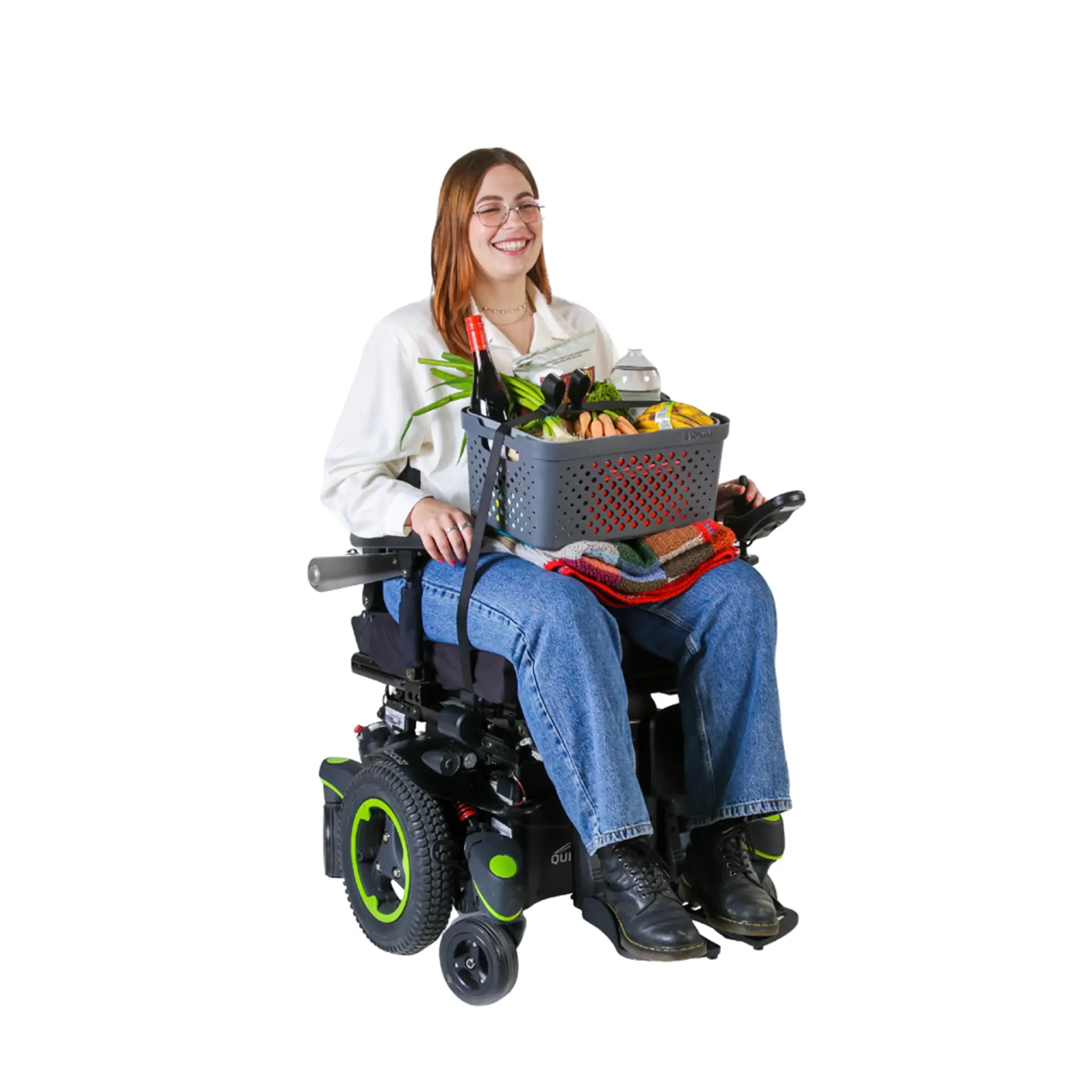 Woman in power wheelchair holding a basket of groceries secured with a strap.